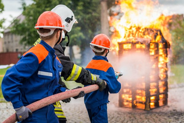 Drei Feuerwehrleute löschen ein Feuer