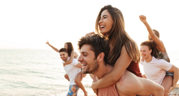 Freunde an Strand nehmen sich Huckepack