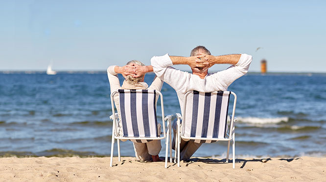 Zwei Personen sitzen in einem Liegestuhl und schauen aufs Meer