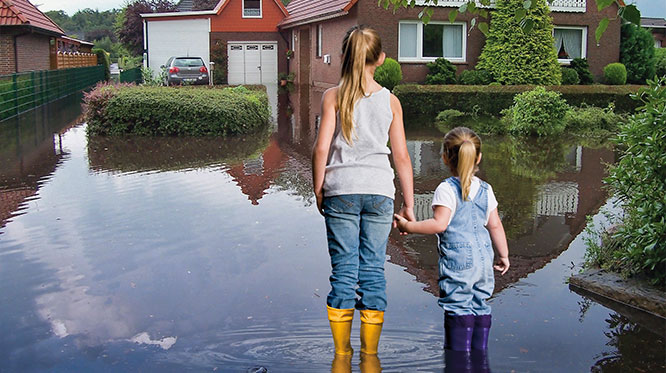 Mutter und Tochter sehen sich eine Überschwemmung an vor einem Haus